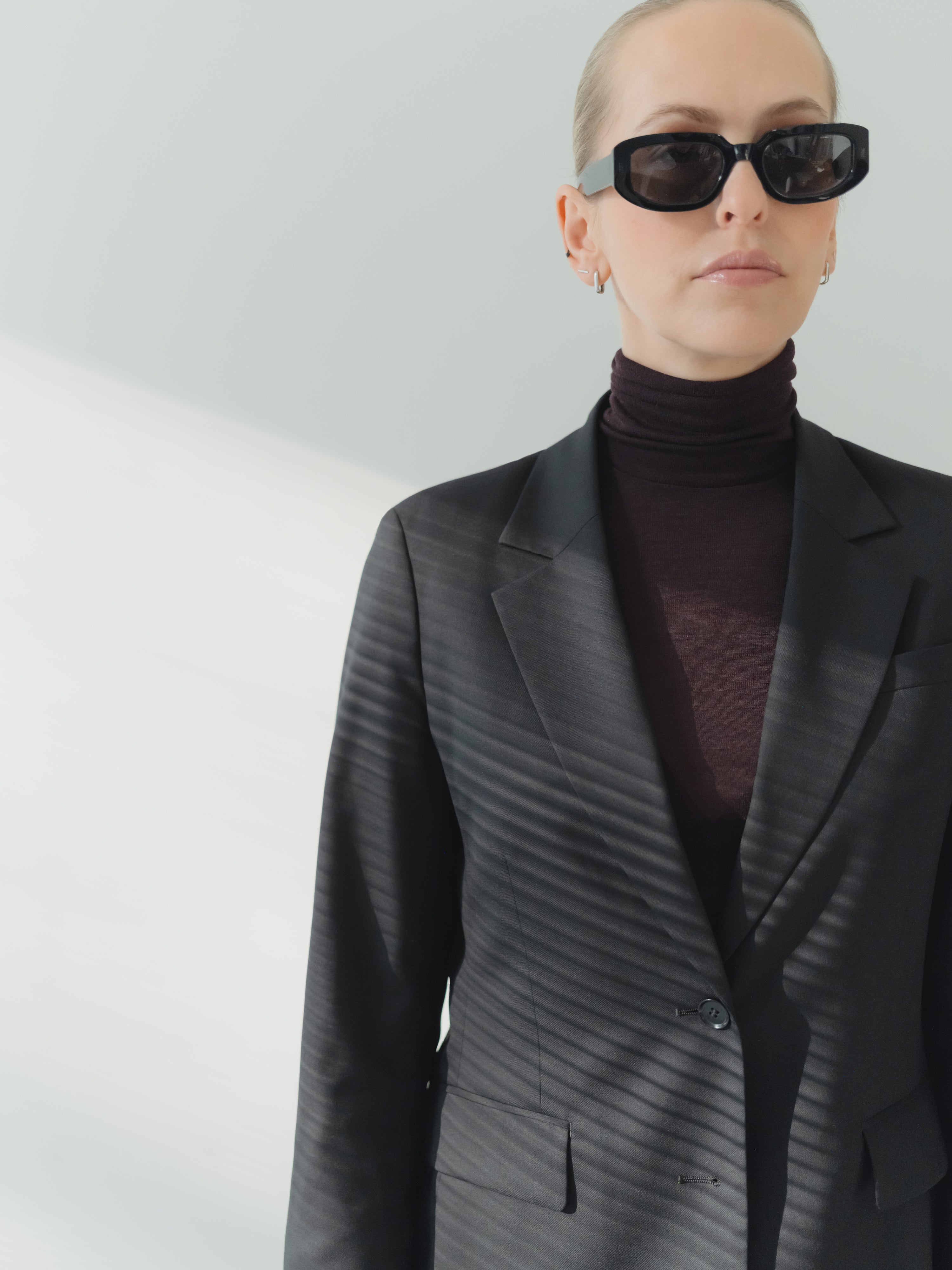 Single-breasted women’s black fine wool stretch twill blazer with notch lapel and flap pockets.