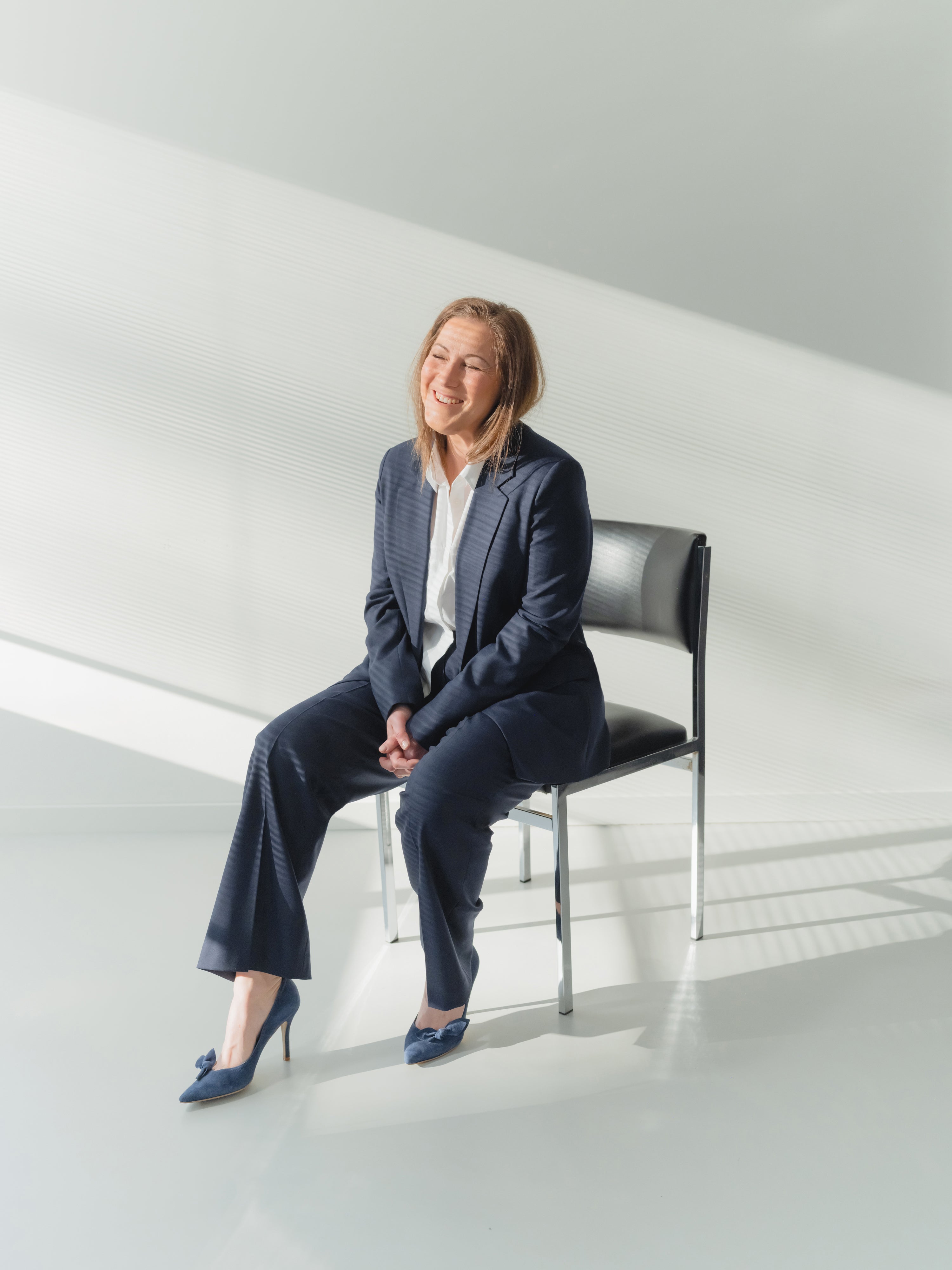 navy single-breasted women’s stretch serge suit with notch lapel blazer and pleated straight-leg trousers.