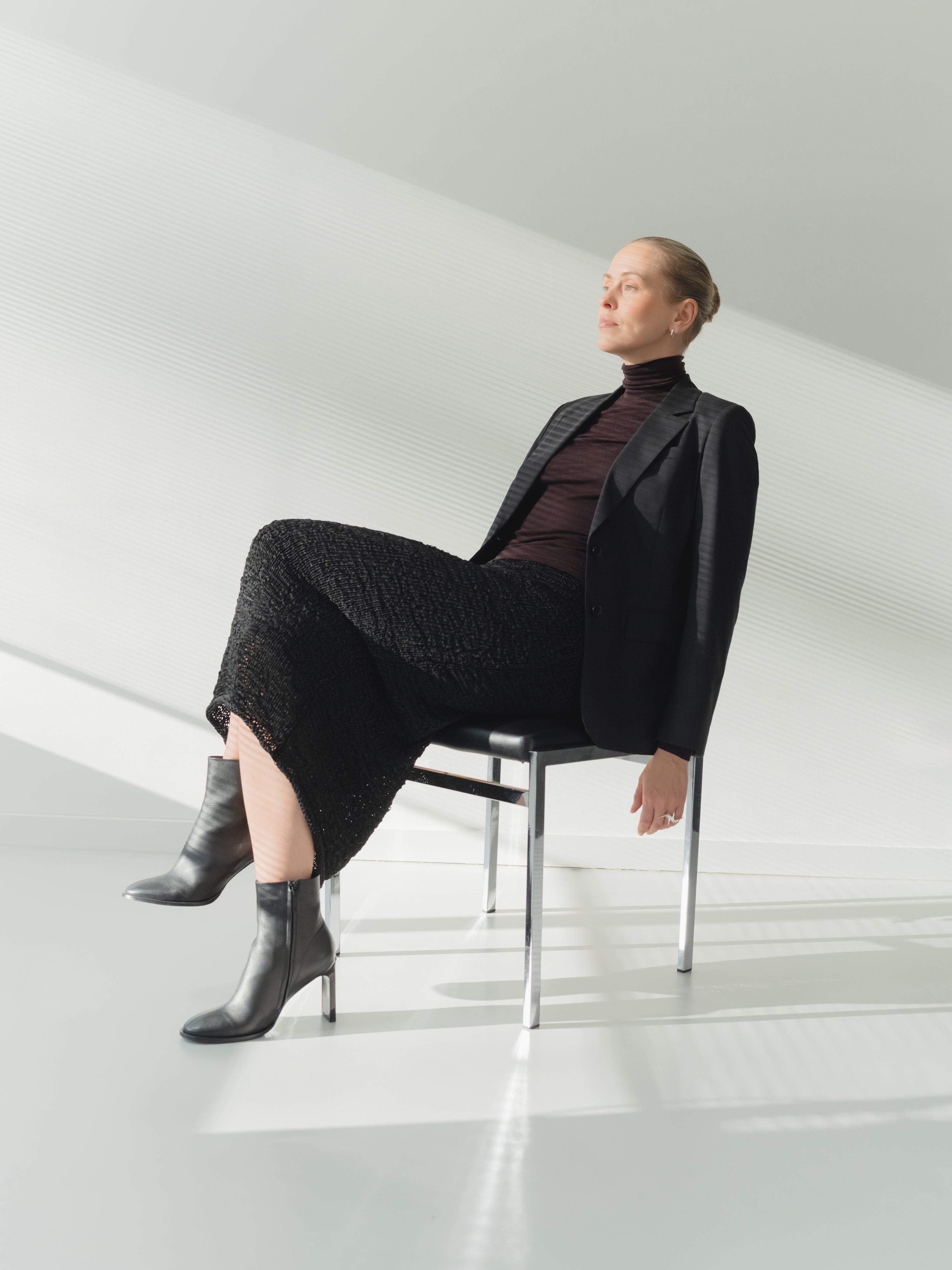 Single-breasted women’s black stretch wool fine twill blazer with notch lapel styled with a skirt.