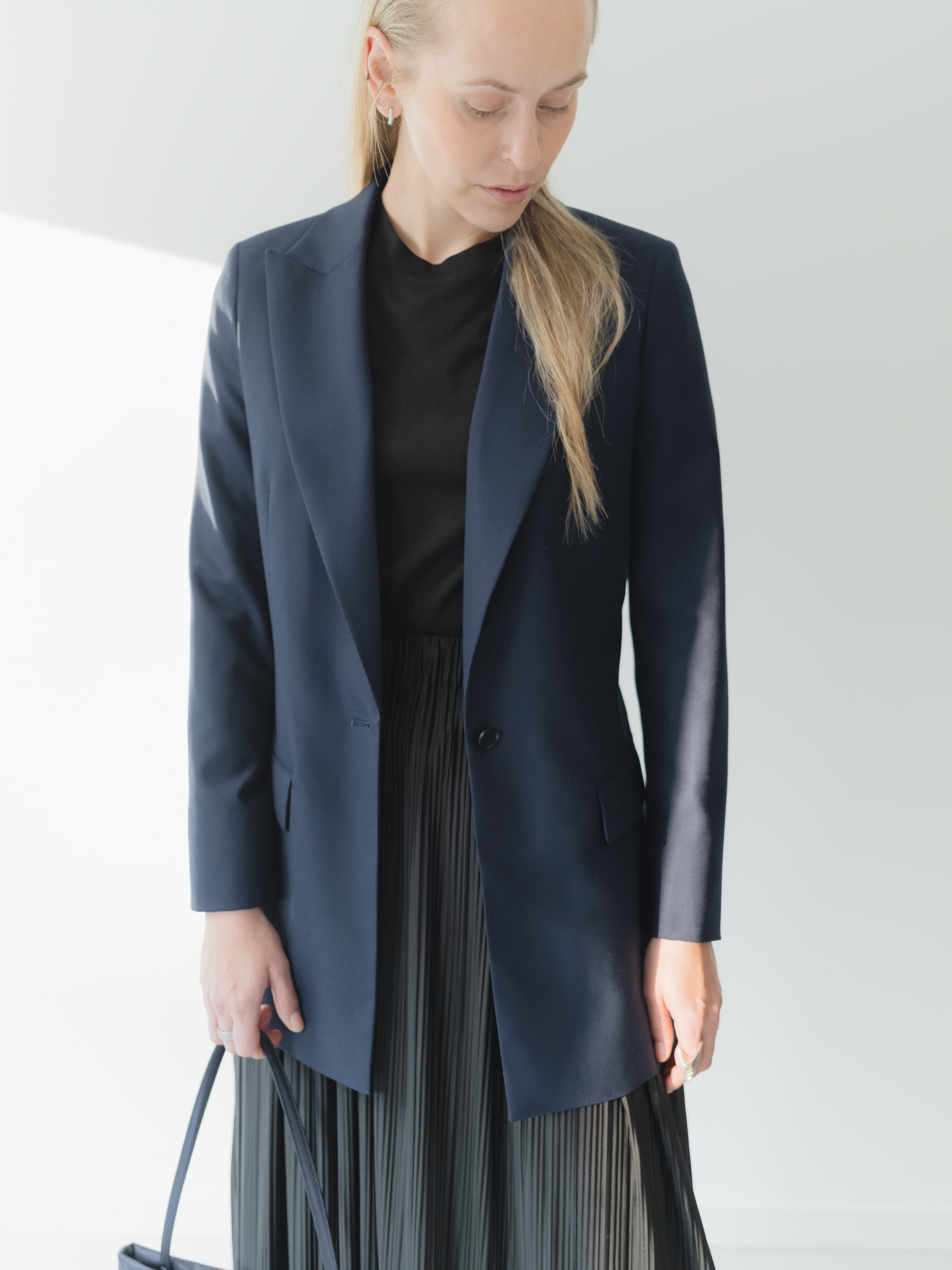 Navy single-breasted women’s peak lapel blazer in mid-weight stretch serge wool styled with a T-shirt and skirt.