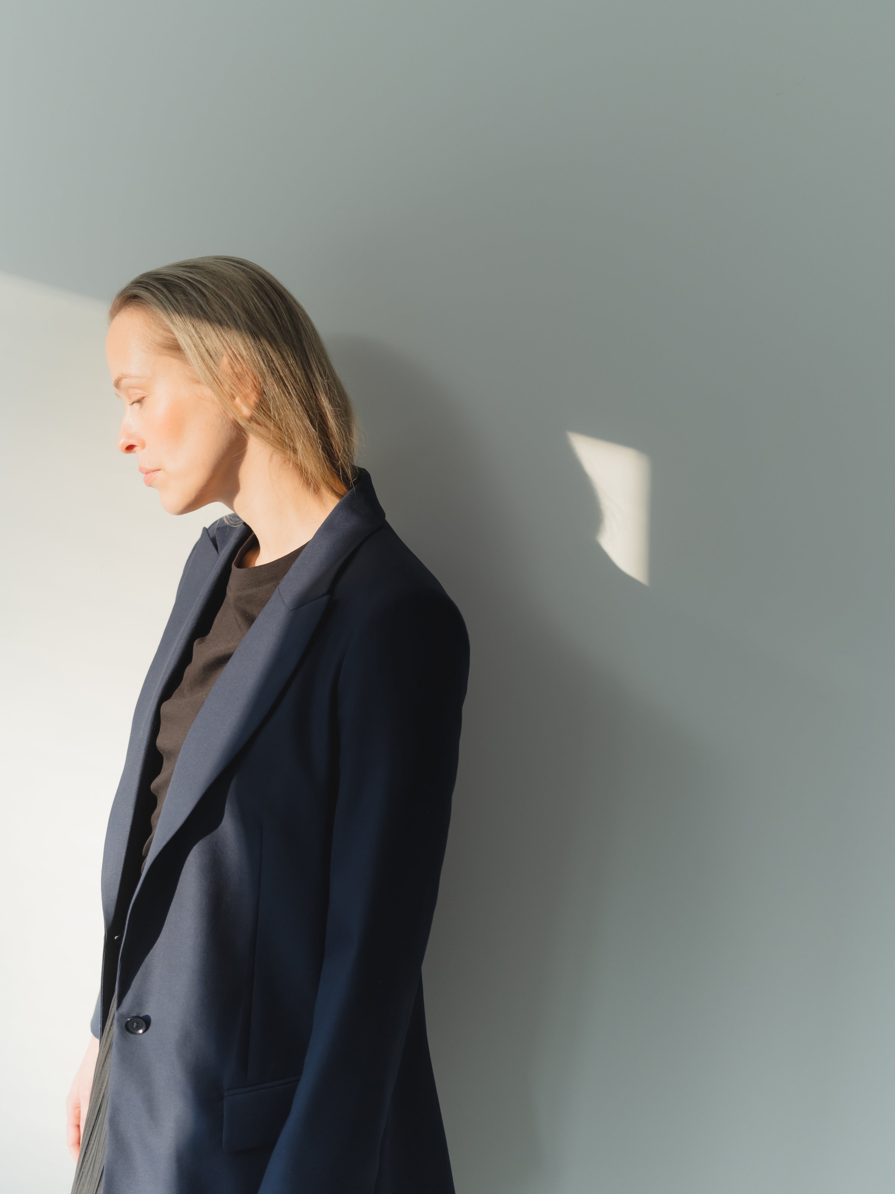 Navy single-breasted women’s peak lapel blazer in mid-weight stretch serge wool styled with a T-shirt and skirt.