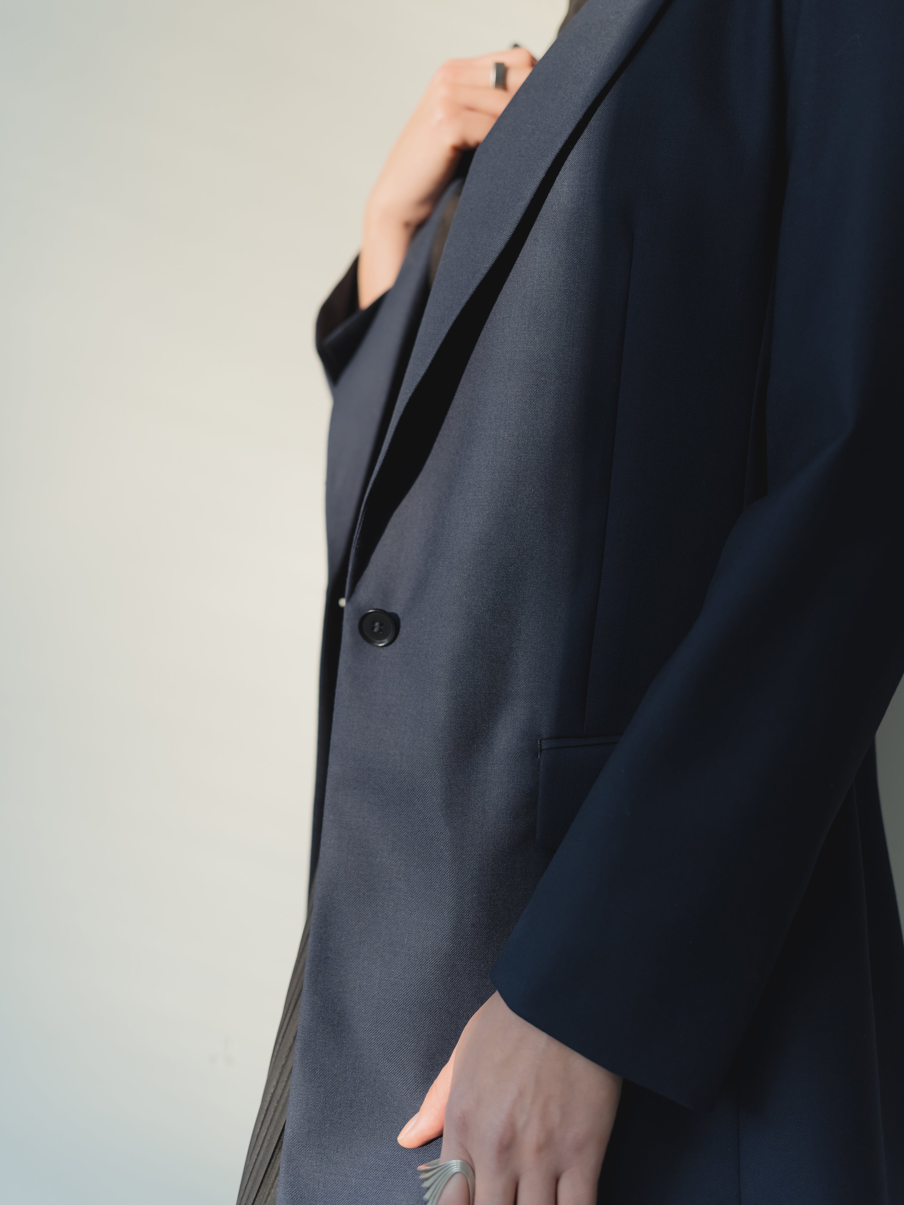 Navy single-breasted women’s peak lapel blazer in mid-weight stretch serge wool styled with a skirt.