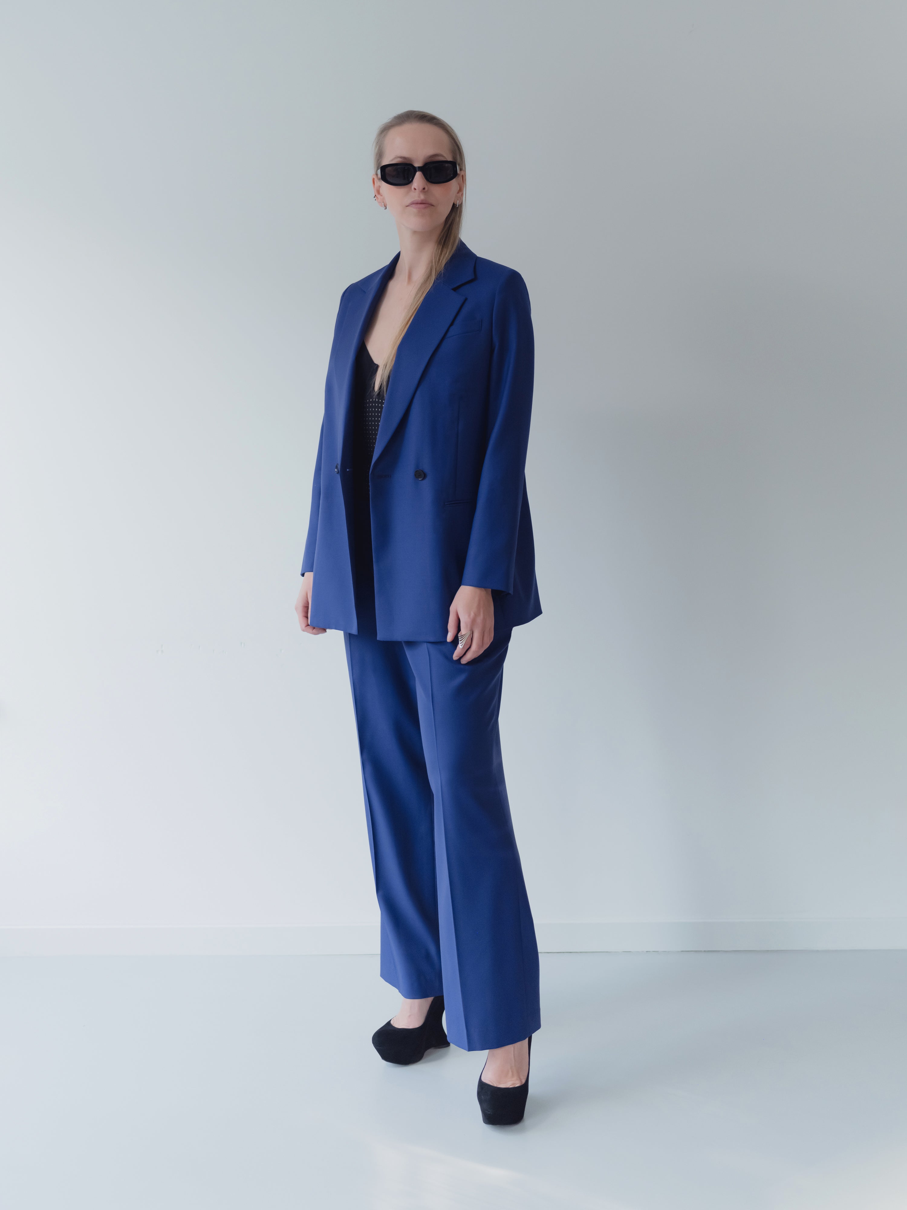 Royal blue double-breasted women’s suit in Super 110’s wool with notch lapel and half-canvas construction. Trousers in straight leg fit with double pleats at waist.