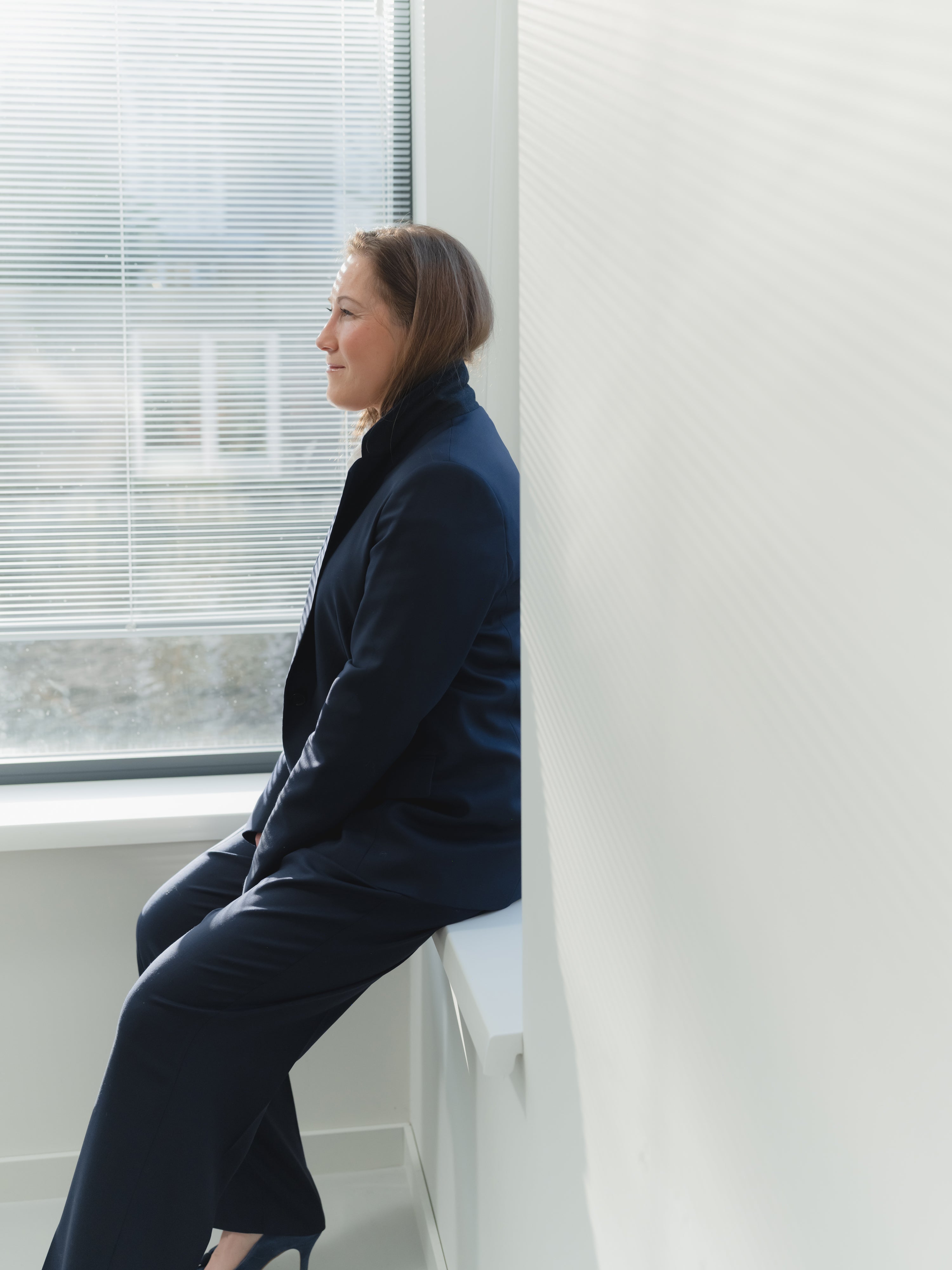 Navy single-breasted women’s stretch serge suit with notch lapel blazer and pleated straight-leg trousers.