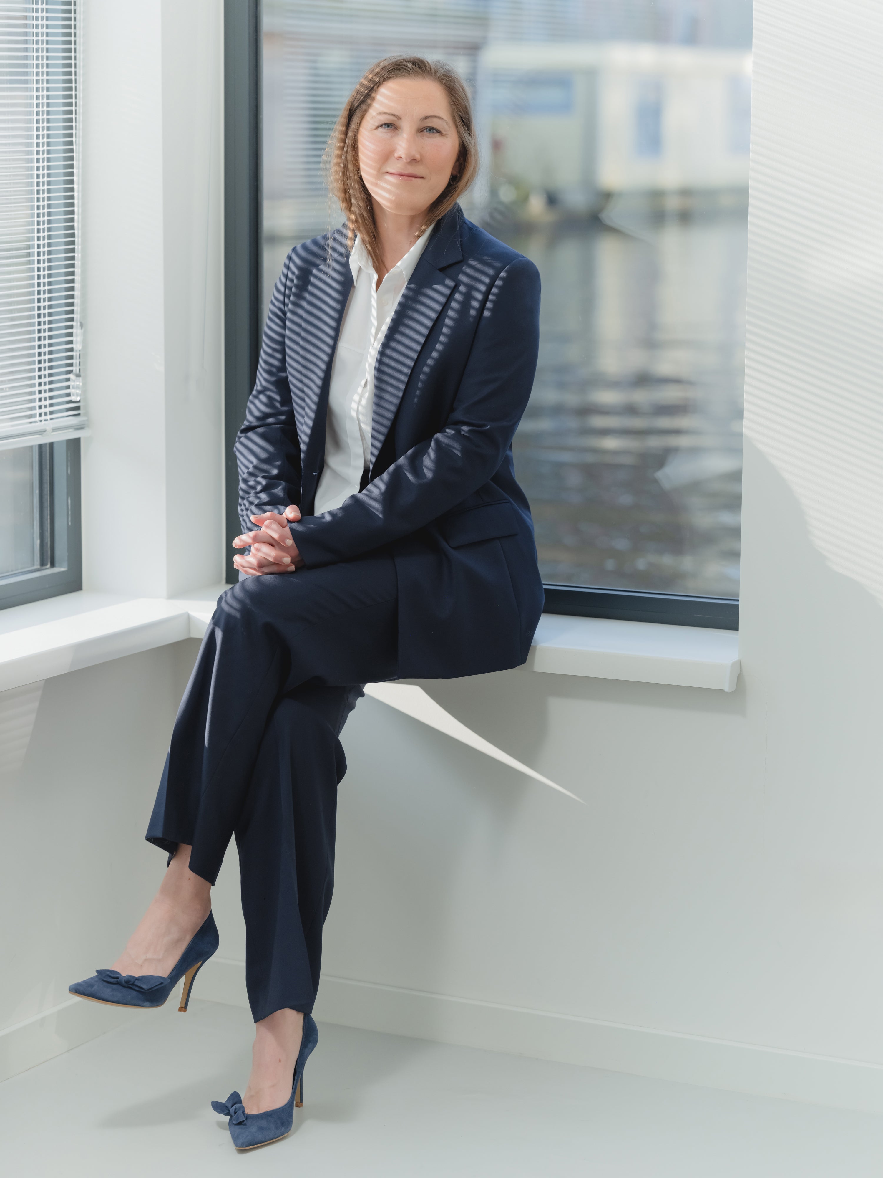 Navy single-breasted women’s stretch serge suit with notch lapel blazer and pleated straight-leg trousers.