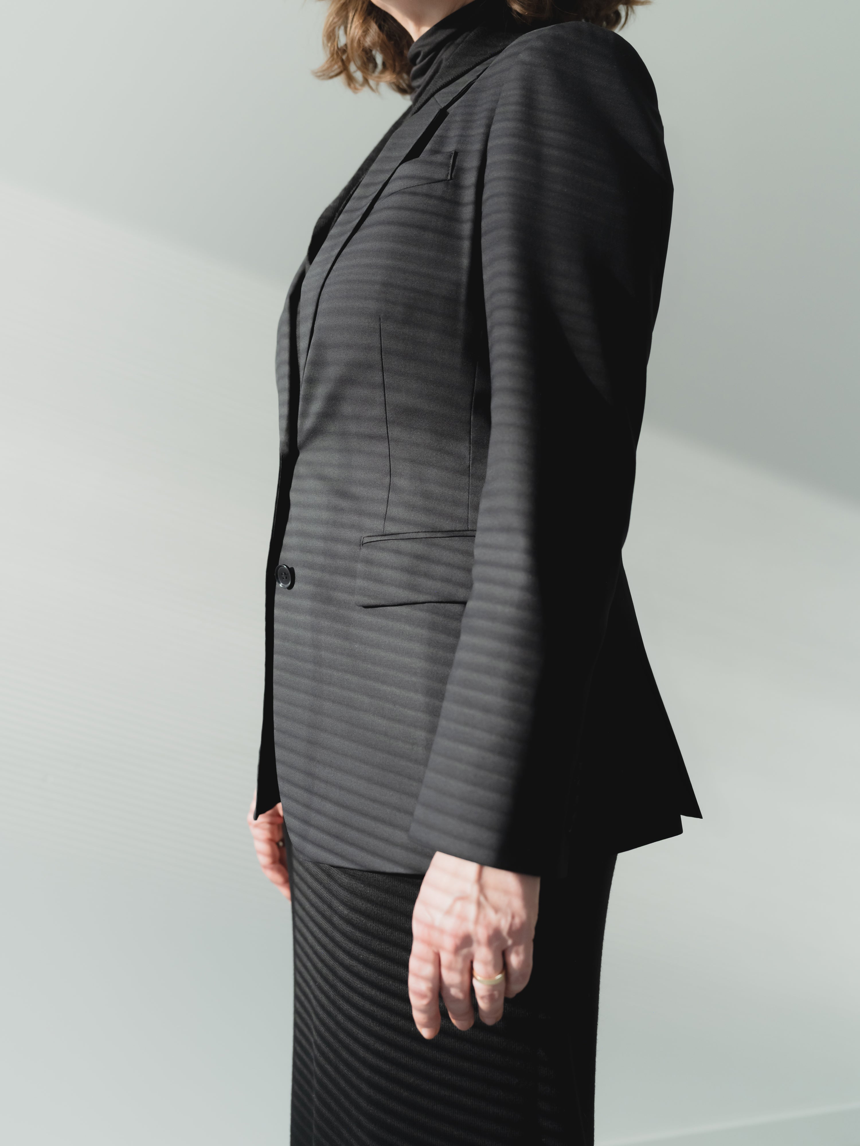 Single-breasted women’s black fine wool stretch twill blazer with notch lapel and flap pockets.