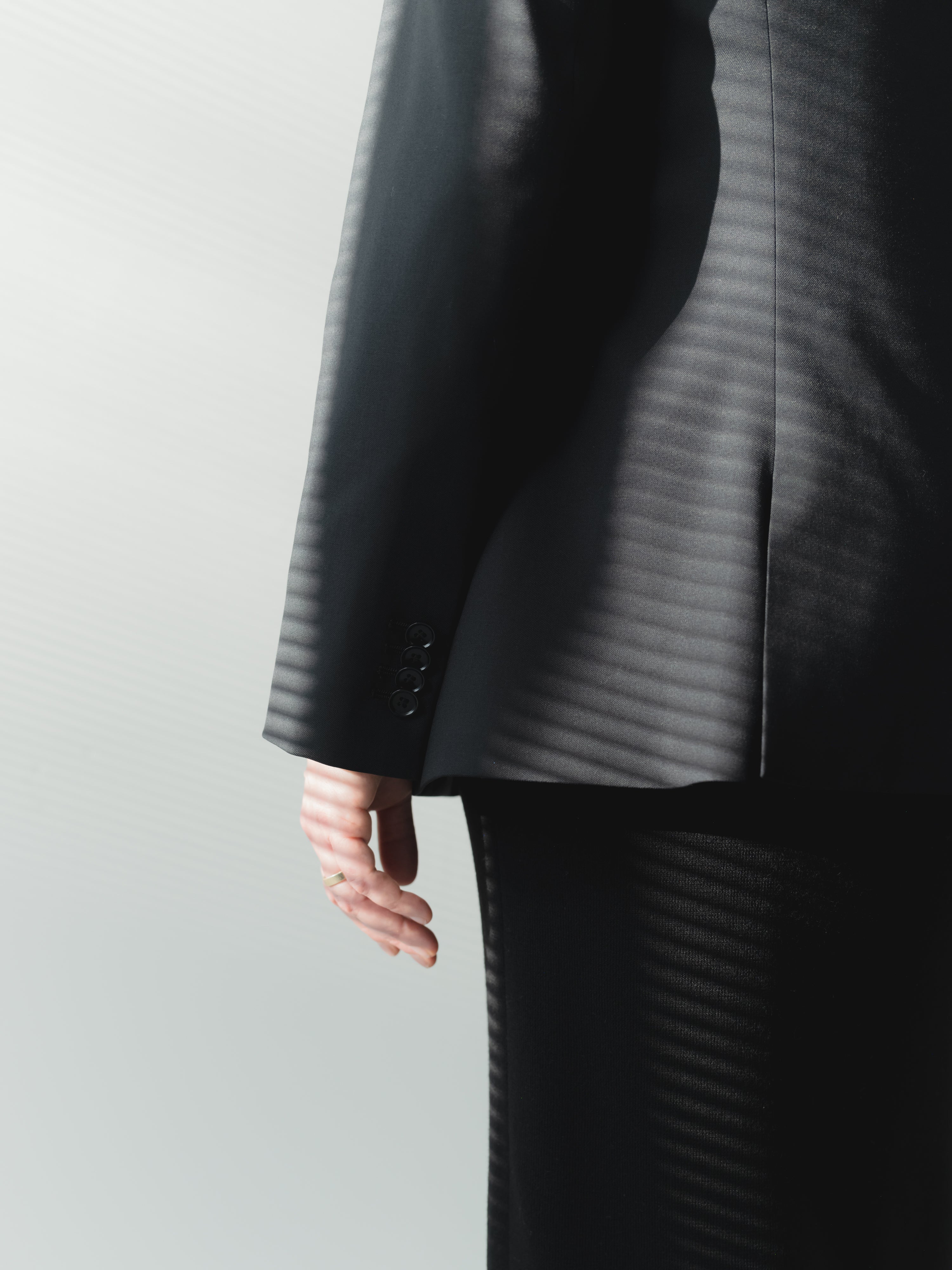 Single-breasted women’s black fine twill stretch wool blazer with side vents and cuff buttons.