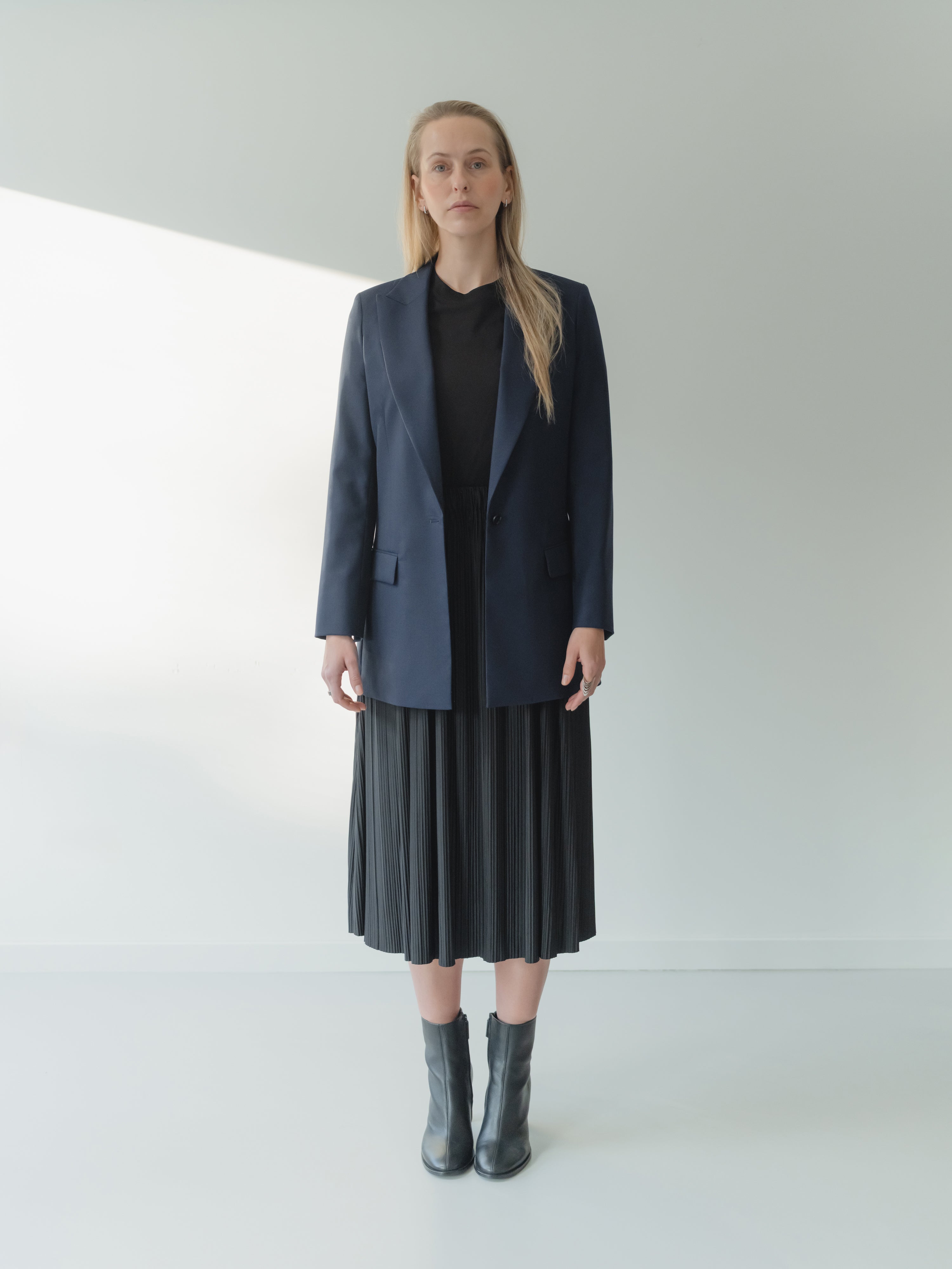 Navy single-breasted women’s peak lapel blazer in mid-weight stretch serge wool styled with a T-shirt and skirt.